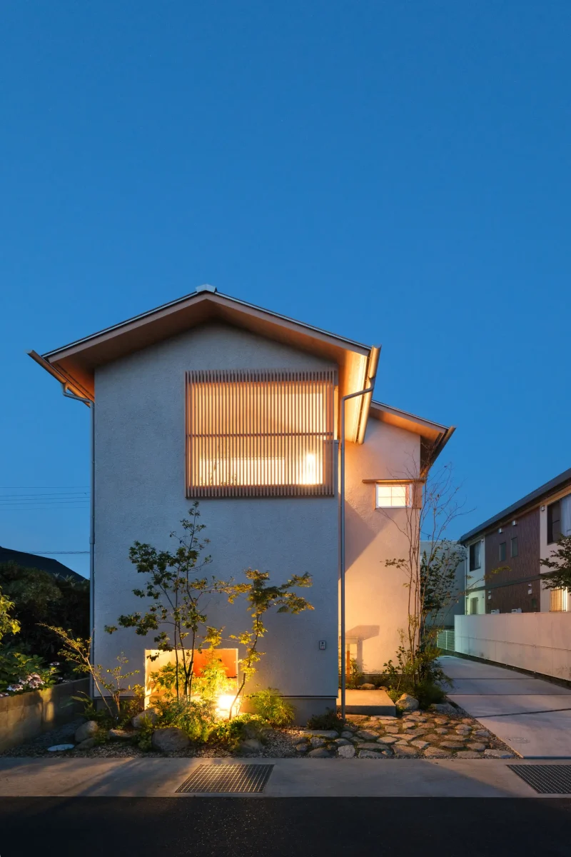 室内の灯りがともる夕暮れの住宅外観